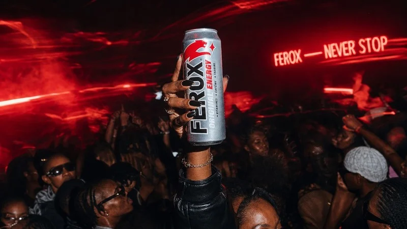 Canette FEROX levée dans une foule, sous les lumières rouges de la nuit